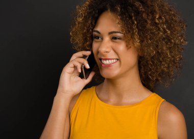 Güzel Afrikalı Amerikalı kadın telefon edip gülüyor.