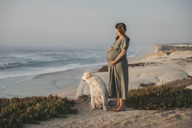 Hamile kadın ve köpeği sahilde.