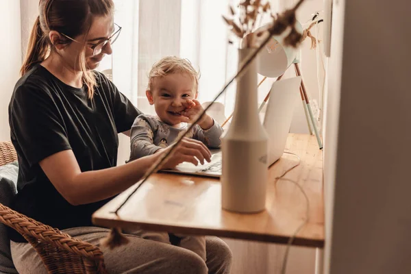 Busy woman working at home with a baby in the la