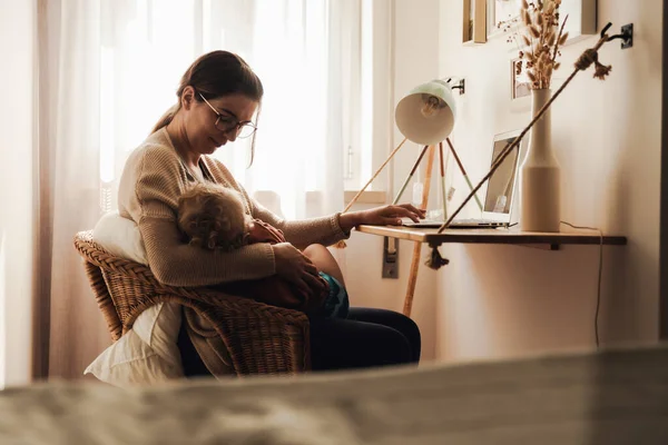 Busy woman working at home with a baby in the la