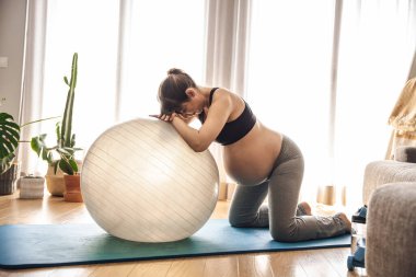 Hamile bir kadın evde spor yapıyor. Spor salonunda spor yapıyor. Bebeği beklerken formda kalmak.