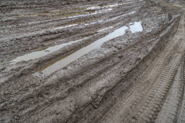 Yağmurdan sonra kırsal bir yol. Toprak yolda yağmur üstüne su birikintileri. Kil, toprak ve su birikintileri bulutlu gün ışığında yağmurdan sonra, sonbahar mevsimi.