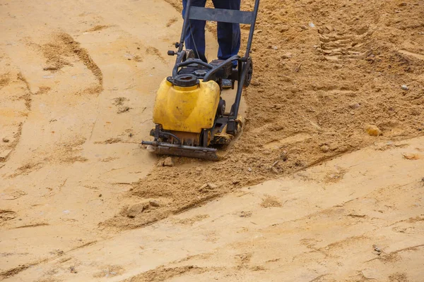 Worker in use vibratory plate compactor for path construction. Plate compactor for compaction sand. — Stock Photo, Image