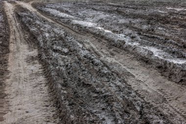 Yağmurdan sonra kırsal bir yol. Toprak yolda yağmur üstüne su birikintileri. Kil, toprak ve su birikintileri bulutlu gün ışığında yağmurdan sonra, sonbahar mevsimi.
