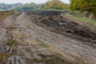 Puslu sonbahar sabahında tarım arazisinin yakınındaki geniş toprak yol