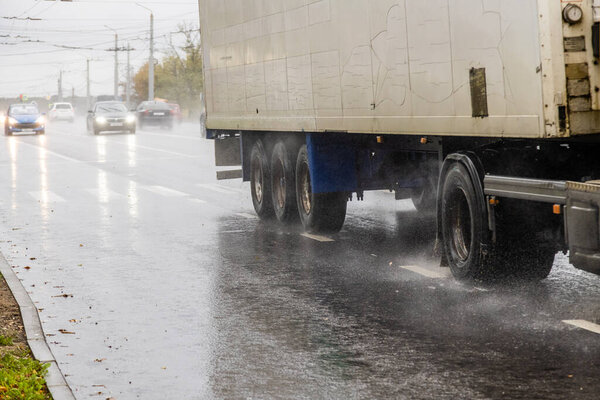 dry van trailer truck moving on a wet road with splashes during the day