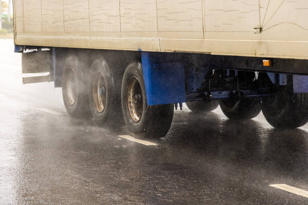 dry van trailer truck moving on a wet road with splashes during the day