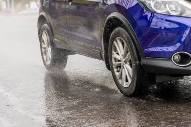Mavi SUV ıslak sonbahar asfalt yolunda koşuyor