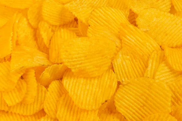 Close-up full frame yellow wavy potato chips heap background — Stok Foto