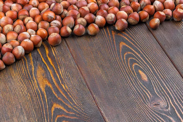 Avelãs com conchas colocadas na superfície da mesa de madeira marrom — Fotografia de Stock