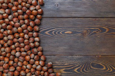 Kahverengi ahşap masa yüzeyinde kabuklu fındıklar var.