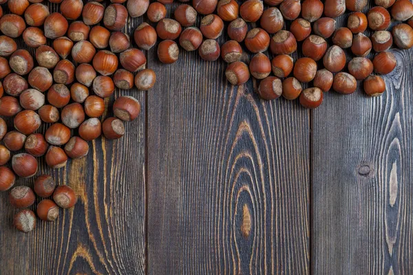 Avelãs com conchas colocadas na superfície da mesa de madeira marrom — Fotografia de Stock