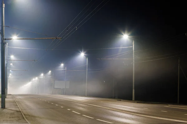 Lege mistige nacht weg met rijen van lantaarnpalen — Stockfoto