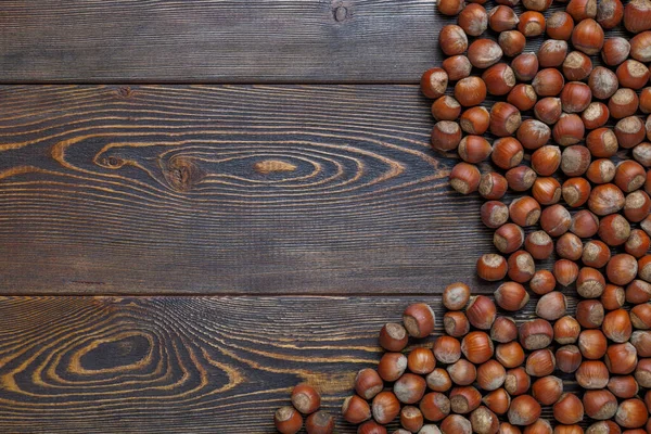 Орехи фундука с оболочками на поверхности коричневого деревянного стола — стоковое фото