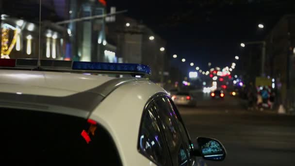 Polisbil ljus flimrar i natten stad med selektivt fokus och bokeh — Stockvideo
