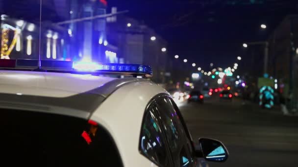 Luzes do carro da polícia piscando na cidade noturna com foco seletivo e bokeh — Vídeo de Stock