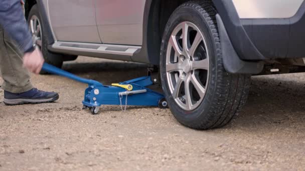 Muž zvedání stříbrné auto s modrým hudraulic podlaha auto jack — Stock video