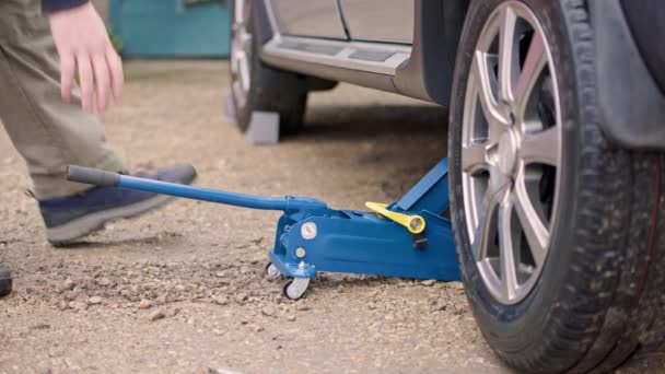 Hombre loweing abajo coche de plata con azul hudraulic gato del coche del piso — Vídeos de Stock