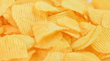 Dönen sarı dalgalı patates cipsi. Tam kare yakın plan.