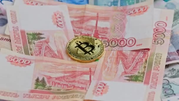 Looped rotation of golden bitcoin shiner on Russian rubles paper banknotes — Stok Video