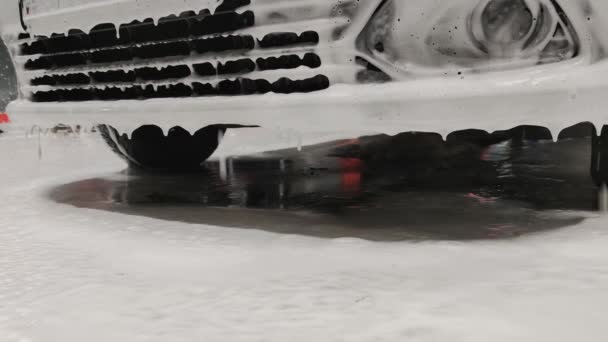Jabón blanco sud cayendo del parachoques delantero del coche durante el lavado de coches en la estación pública, vista de ángulo bajo estática de primer plano — Vídeos de Stock