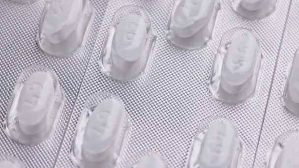 Vita tabletter ovala tabletter blister med närbild snurrande eller roterande makro bakgrund — Stockvideo