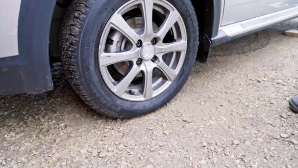 Pessoa que coloca choques de roda sob a roda do pneu do veículo civil para impedir a sua circulação — Vídeo de Stock