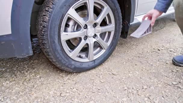 Osoba umístění volantu pod kolo civilního vozidla pneumatiky, aby se zabránilo jeho pohybu — Stock video
