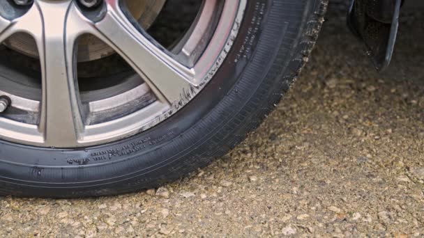 Persona que coloca y retira la muesca de la rueda debajo de la rueda del neumático del vehículo civil para evitar su movimiento — Vídeo de stock
