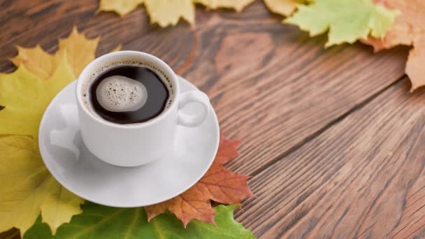Kávé csésze fa asztalon színes őszi juharfalevelek forgó kávé buborékok — Stock videók