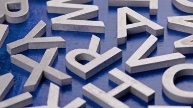 Düz mavi renkli yüzey üzerinde gümüş metal harflerin tam kare yakın çerçeve döndürme arka planı