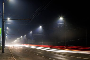 Boş sisli gece yolu ve sıra sıra lamba direkleri