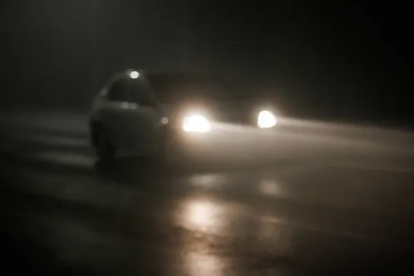 Foto desfocada de carro embaçado em movimento na noite vazia estrada nebulosa — Fotografia de Stock