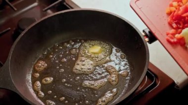 Kızartma için eritilmiş tereyağlı tavaya taze sebze ekleyen kadının yakın çekim görüntüsü 4 kez yavaşlatılmış.