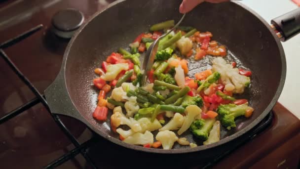 用不锈钢勺子在平底锅里搅拌蔬菜，同时在平底锅里煎，特写 — 图库视频影像