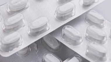 Beyaz oval tablet hapları yakın çekimde dönerek veya dönerek makro medikal arka plan metformin hidroklorür 850 mg