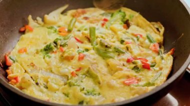 Spatula ile el taze sebzelerle omlet dilimleme.