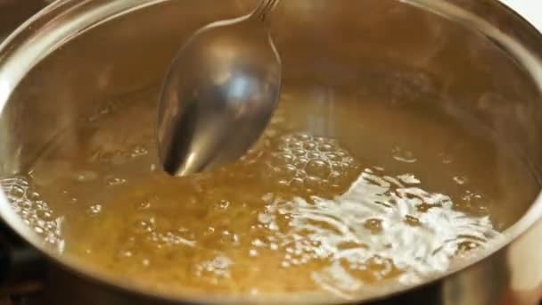 Mão branca caucasiana mexendo macarrão fervendo em água com uma colher — Vídeo de Stock