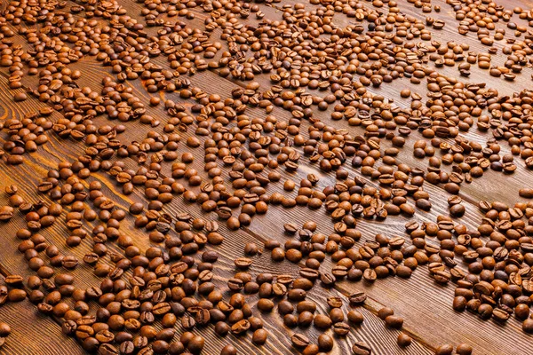 Жареный кофейный зёрна распространяются по деревянной доске - полный фон рамы — стоковое фото