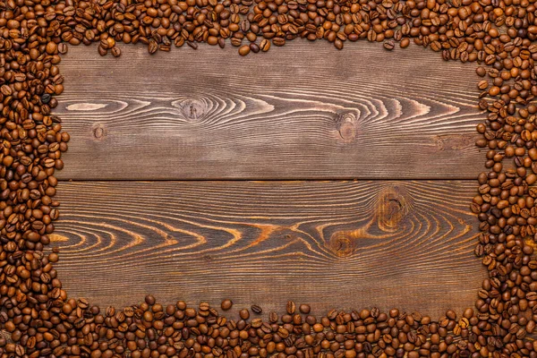 Rectangular frame of many roasted coffee beans on brown wooden surface — Stock Photo, Image