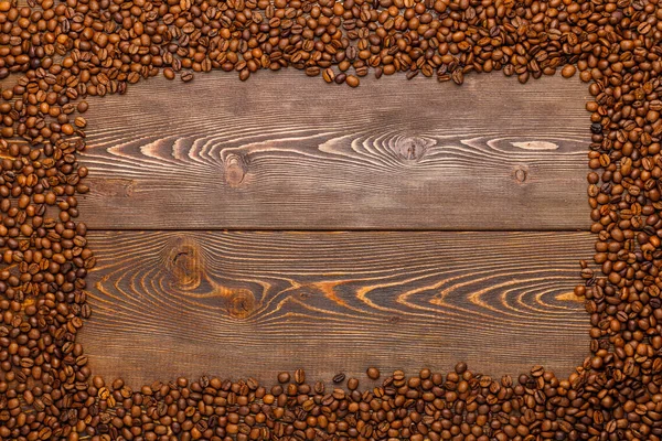 Rectangular frame of many roasted coffee beans on brown wooden surface — Stock Photo, Image