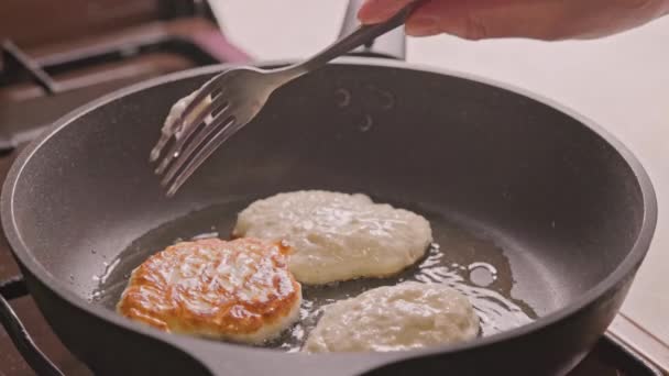 Dłonie z dwoma widelcami przerzucającymi półpłynne ciasto pieczone na żeliwnej patelni pokrytej olejem roślinnym — Wideo stockowe