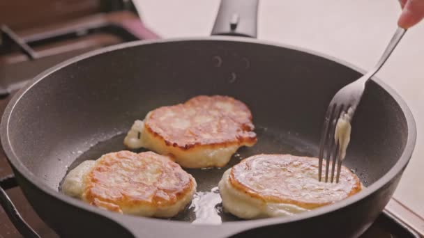 Mano con tenedor volteo panqueques domésticos tostado en la sartén de hierro fundido cubierto con aceite vegetal — Vídeo de stock