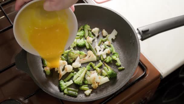 Θηλυκά χέρια προσθέτει μια ομελέτα σε τηγανητά λαχανικά, ενώ το μαγείρεμα ομελέτα — Αρχείο Βίντεο