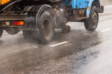 Yağmurlu bir günde asfalt yolda ilerleyen eski bir kamu kamyonu. Yakın plan.