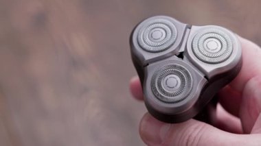 Kafkas elleri içinde talaş ve deri parçacıkları olan elektrikli traş makinesinin kafasını açıyor.