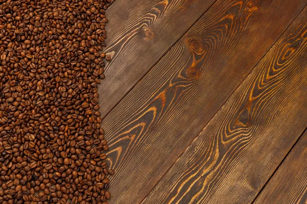 Roasted coffee beans laid on brown wooden table surface — Stock Photo, Image
