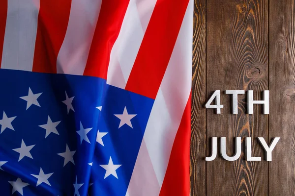 Sanat 4th heinäkuu ja rypistynyt USA lippu tasainen kuvioitu puinen pinta tausta — kuvapankkivalokuva