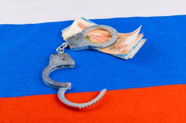 Rus kağıt rublesi ve bitcoin parlatıcısı. Kelepçelenmiş olarak Rusya bayrağı arka planında.