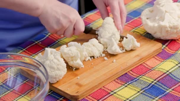 Elder caucasian woman cutting raw white cauliflower on bamboo cutting board — Stockvideo